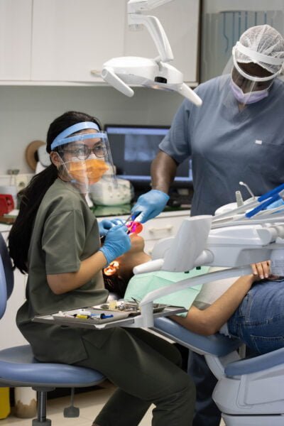 Dr Lahlou Salma assise sur une chaise de dentiste avec un masque.